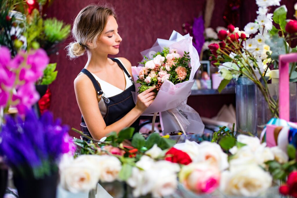 Florist woman creates flower bouquet of mixed flowers for delivery to client